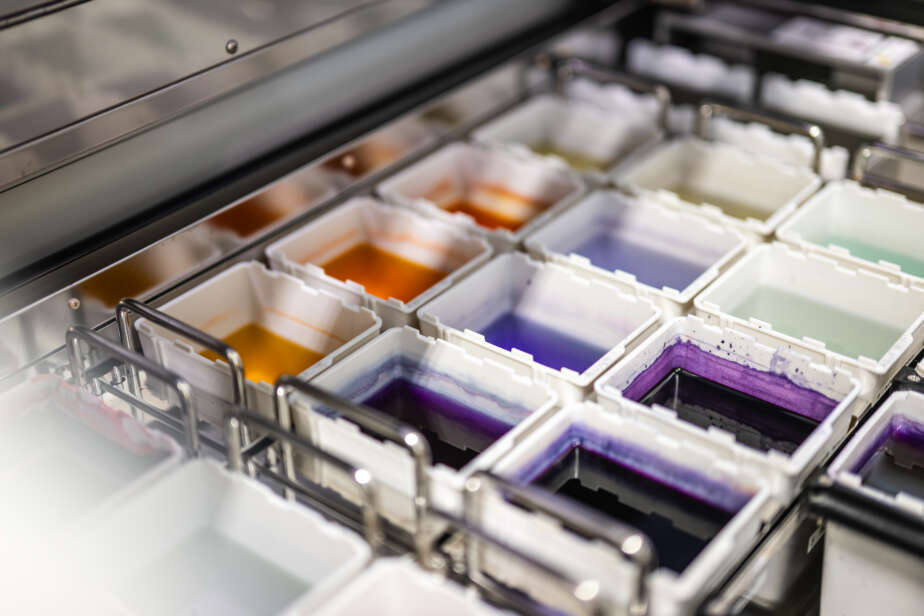 Reihe von Farbbechern in verschiedenen Farben, angeordnet in einem Metallgestell.