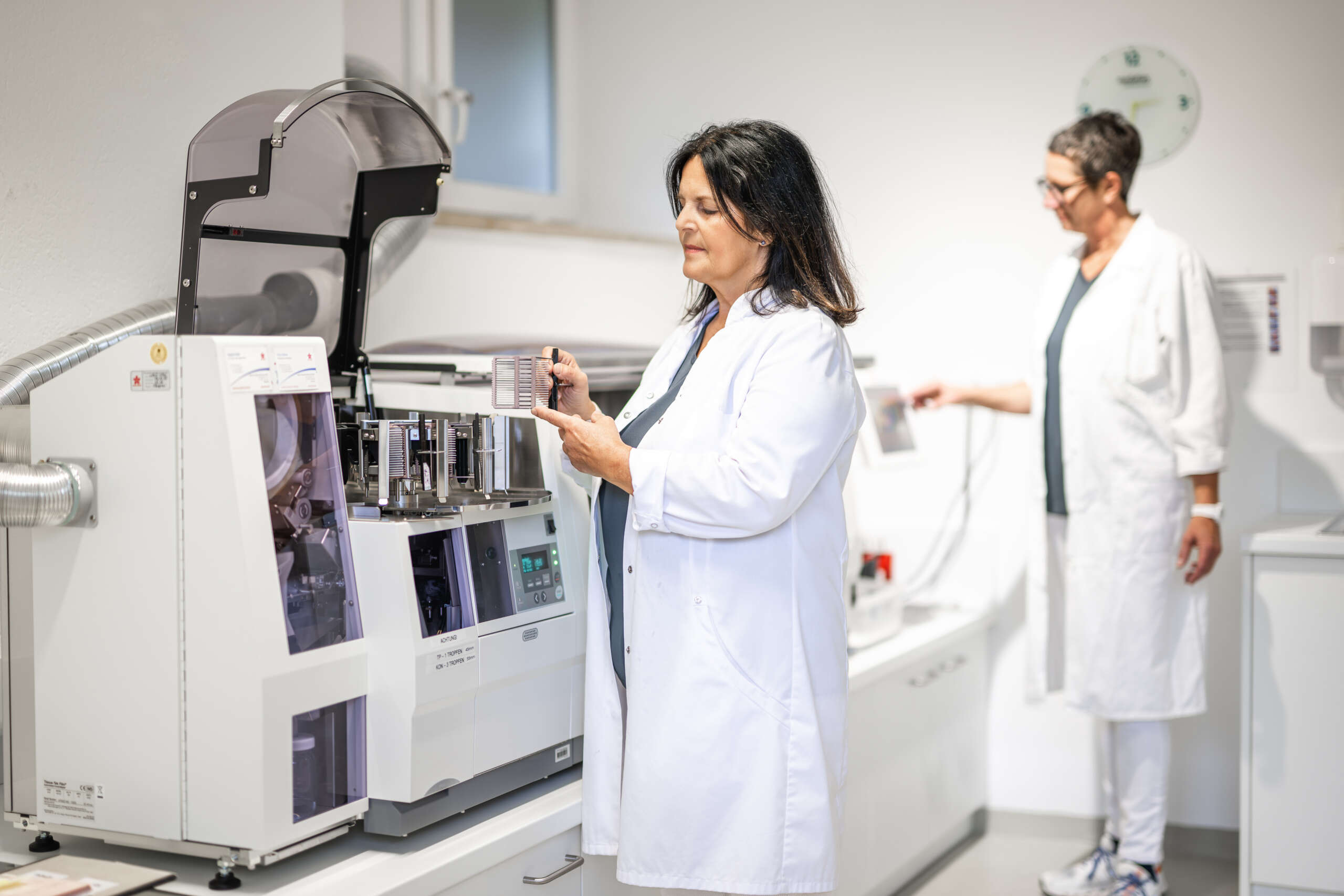 Laborantin in einem weißen Kittel bedient ein Analysegerät in einem modernen Labor.