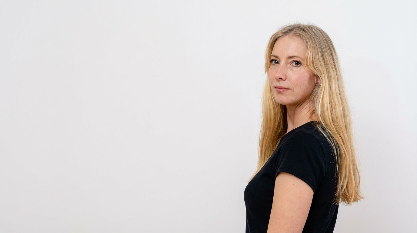 Frau mit langen blonden Haaren, die in einem schwarzen T-Shirt seitlich zur Kamera schaut.