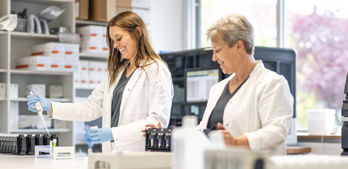 Zwei Laborangestellte in weißen Laborkitteln verwenden Pipetten in einem modernen Labor.